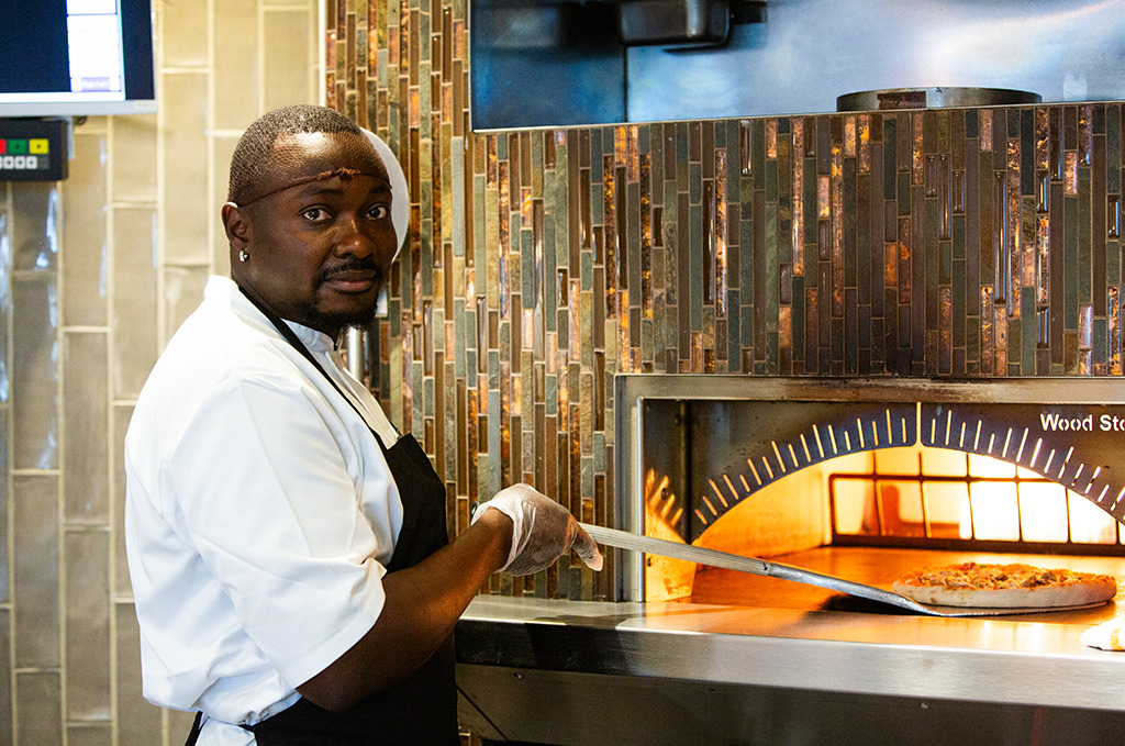 Collington chef putting pizza in oven