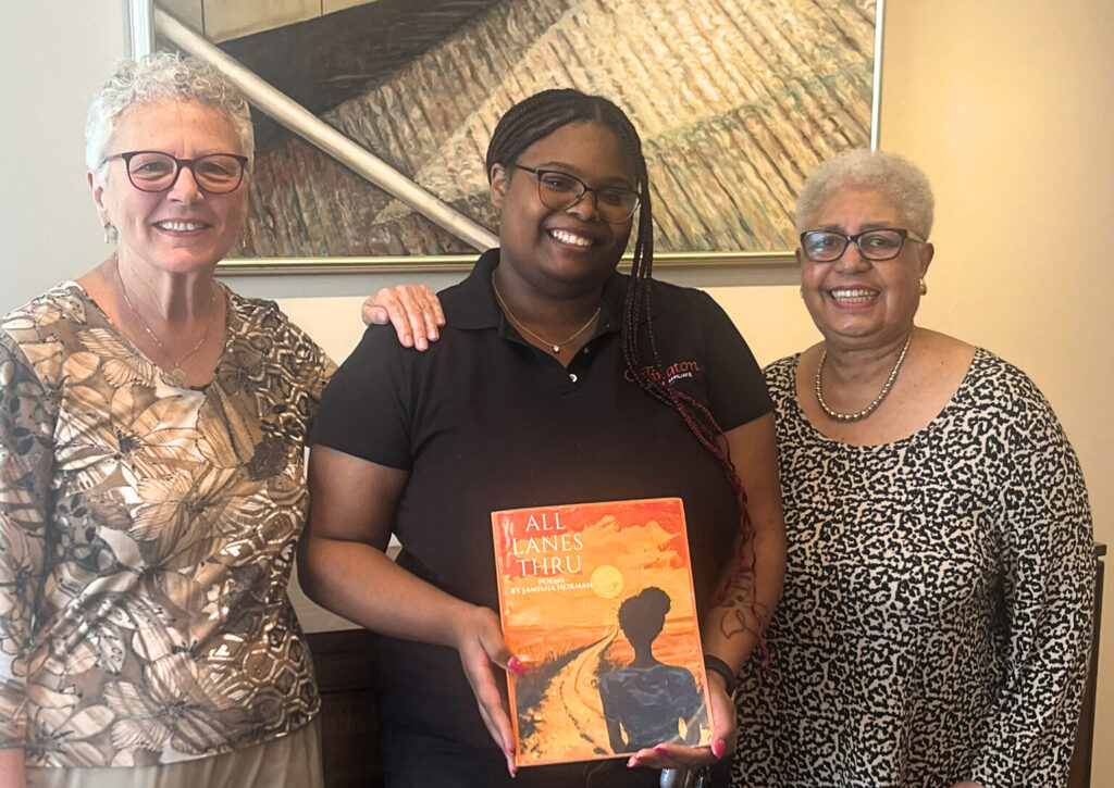 Jamisha holding her poetry book, All Lanes Thru with residents